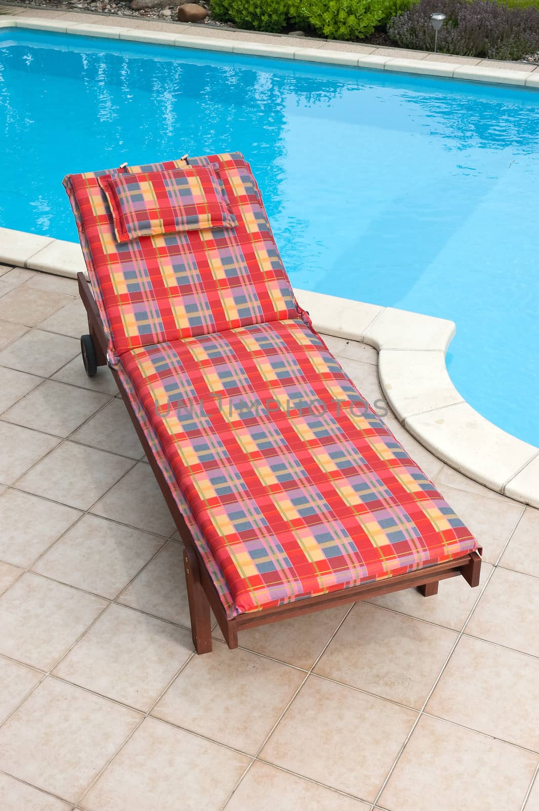 Wooden garden deckchair standing by the pool