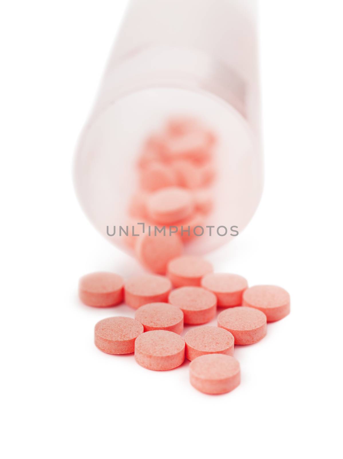 Macro view of heap of red pills spilled out of container over white background