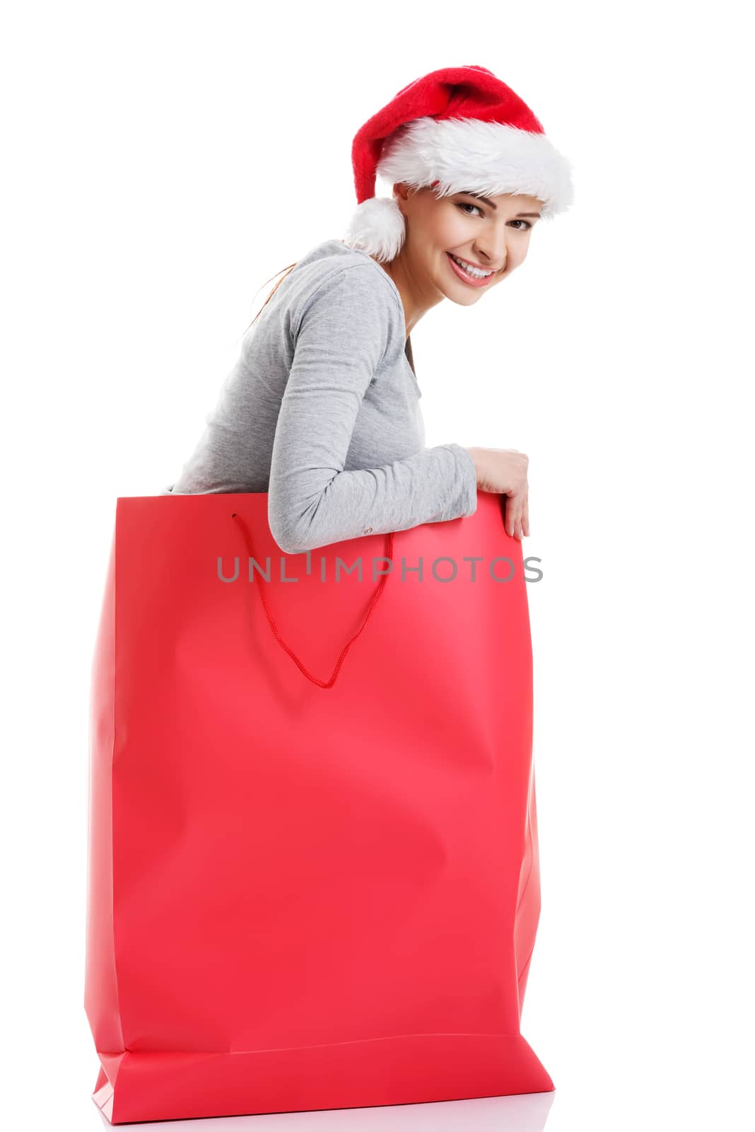 Beautiful girl wearing santa hat in red shopping bag. Isolated on white.