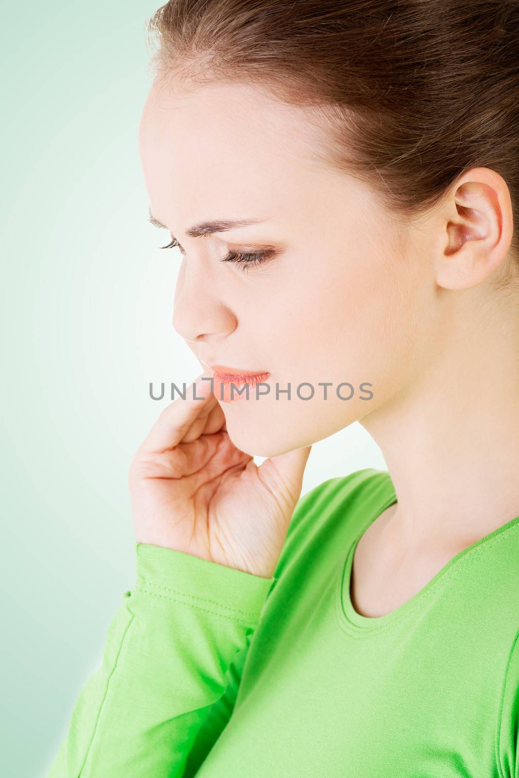 Teen woman pressing her bruised cheek with a painful expression as if she's having a terrible tooth ache.