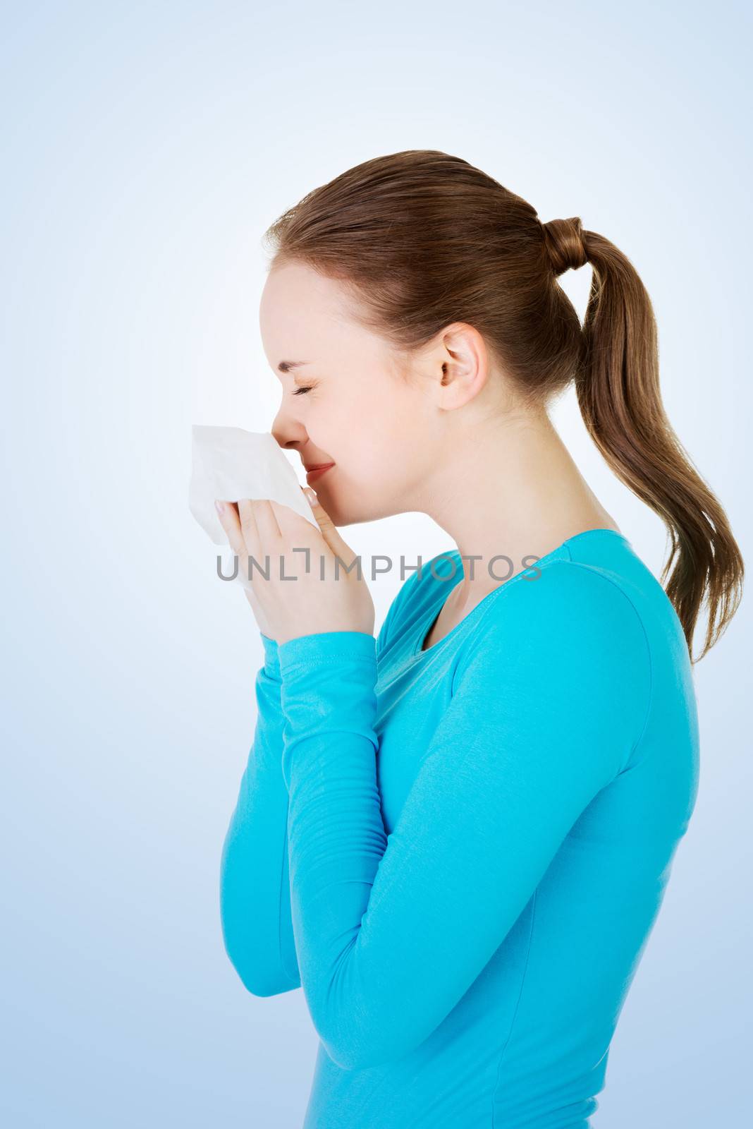 Young woman with tissue - sneezing. Allergy or cold.