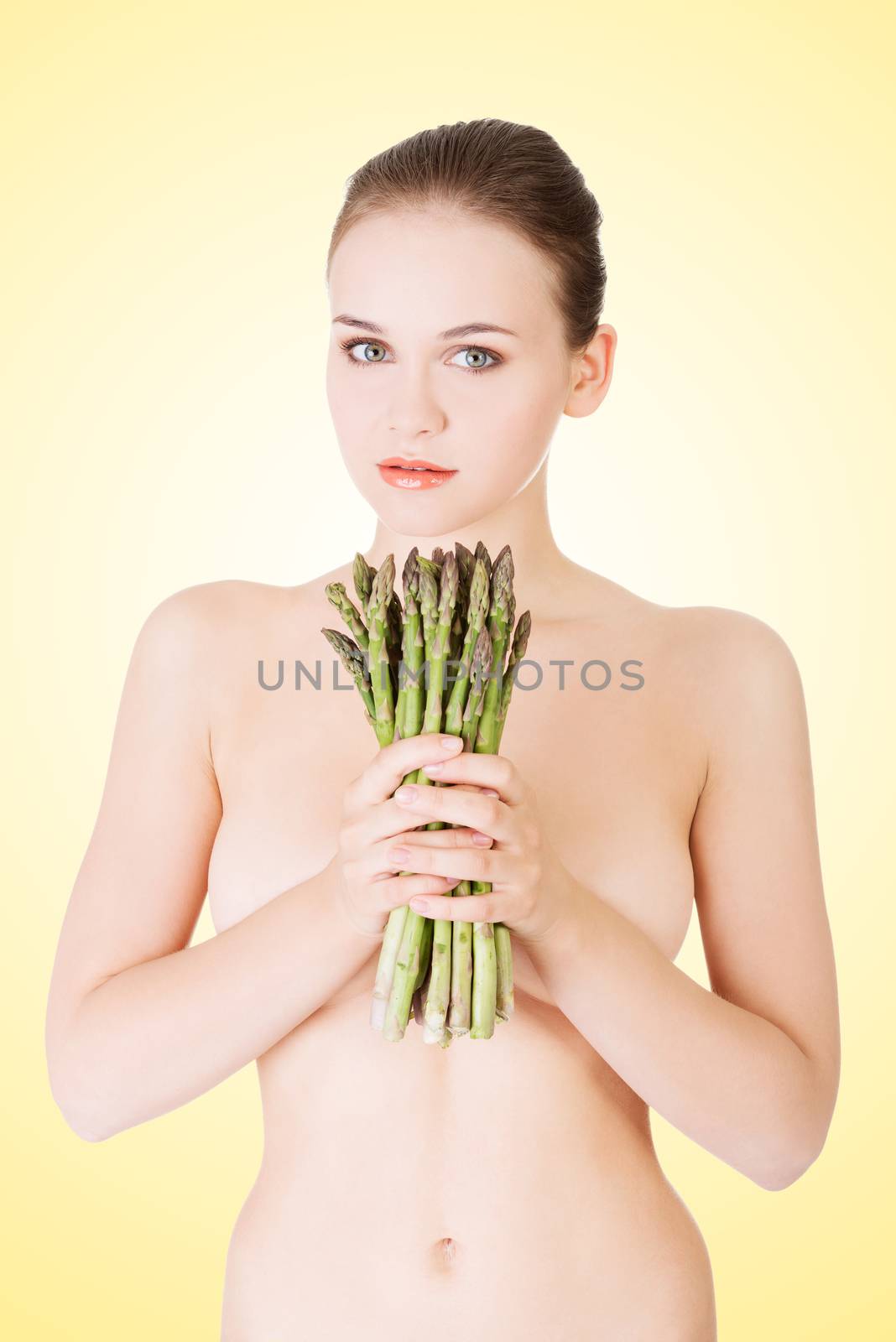 Beautiful fit woman with asparagus, over yellow