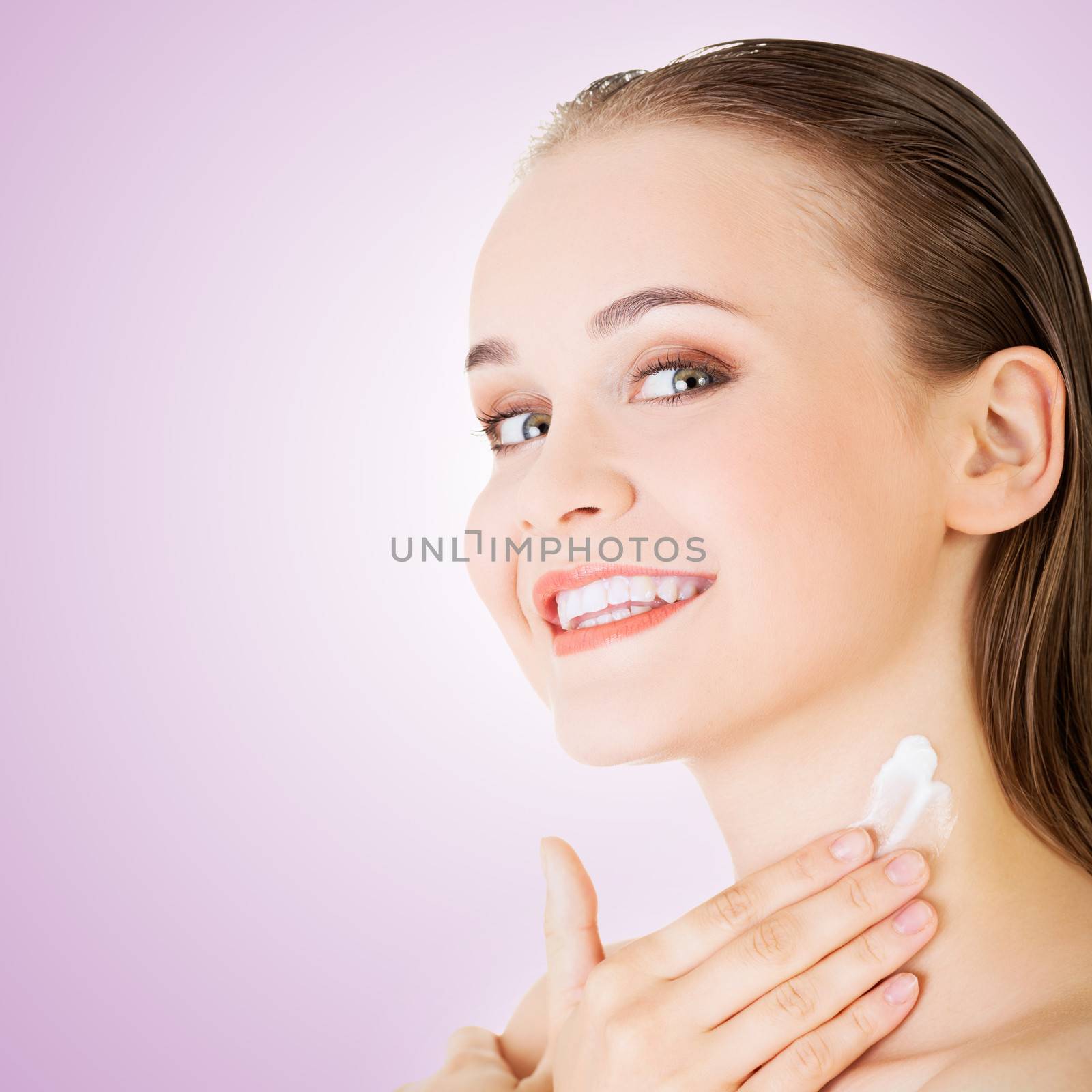 Beautiful woman with healthy skin applying cosmetic cream on a clean fresh face