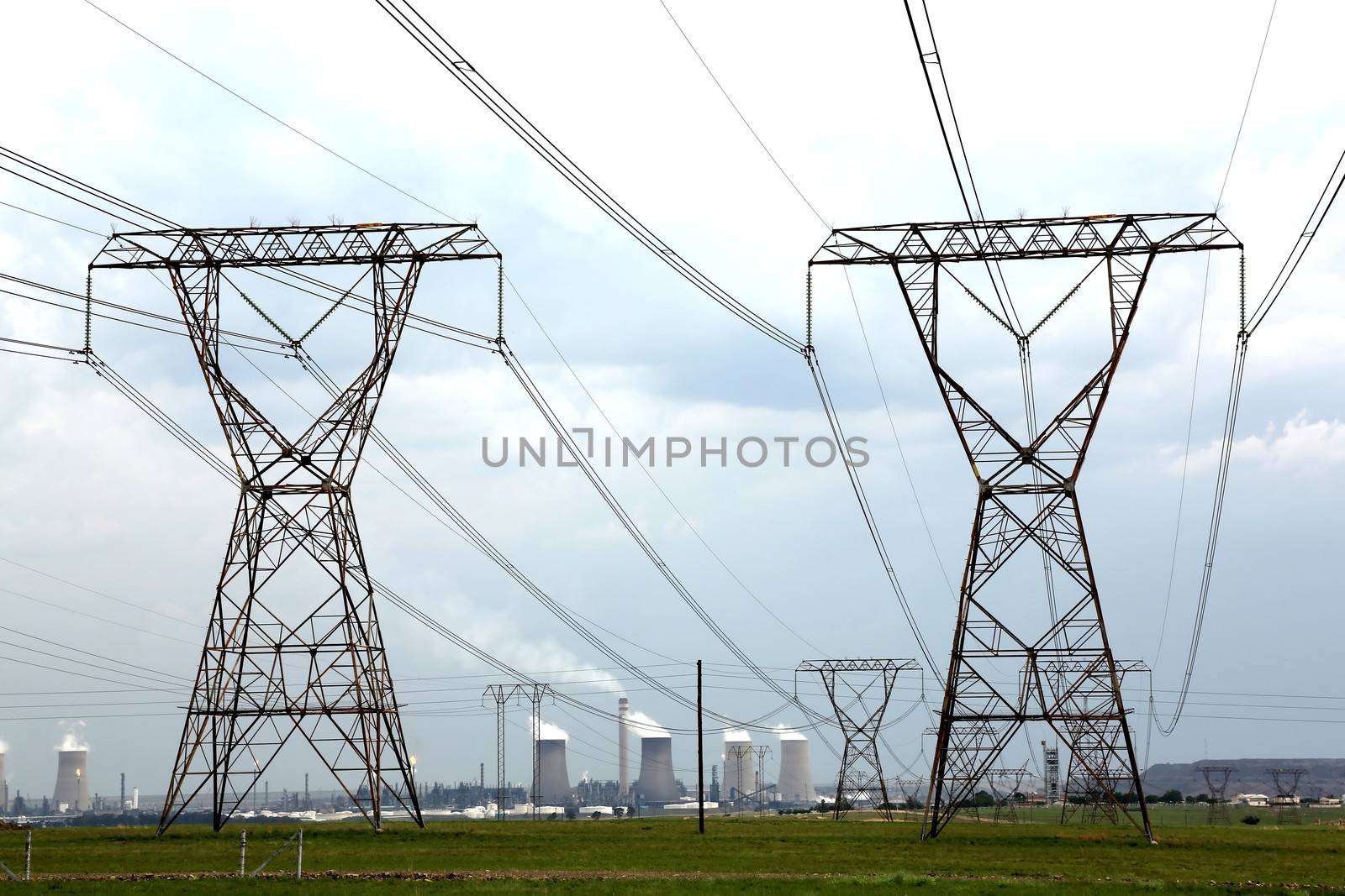 Electricity pylons with energy and fuel production plant in the background