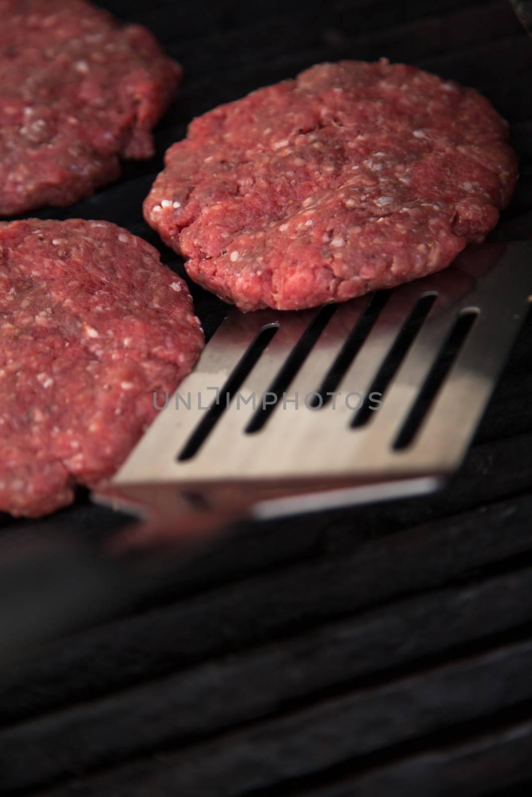 Raw hamburgers on the grill by Izaphoto