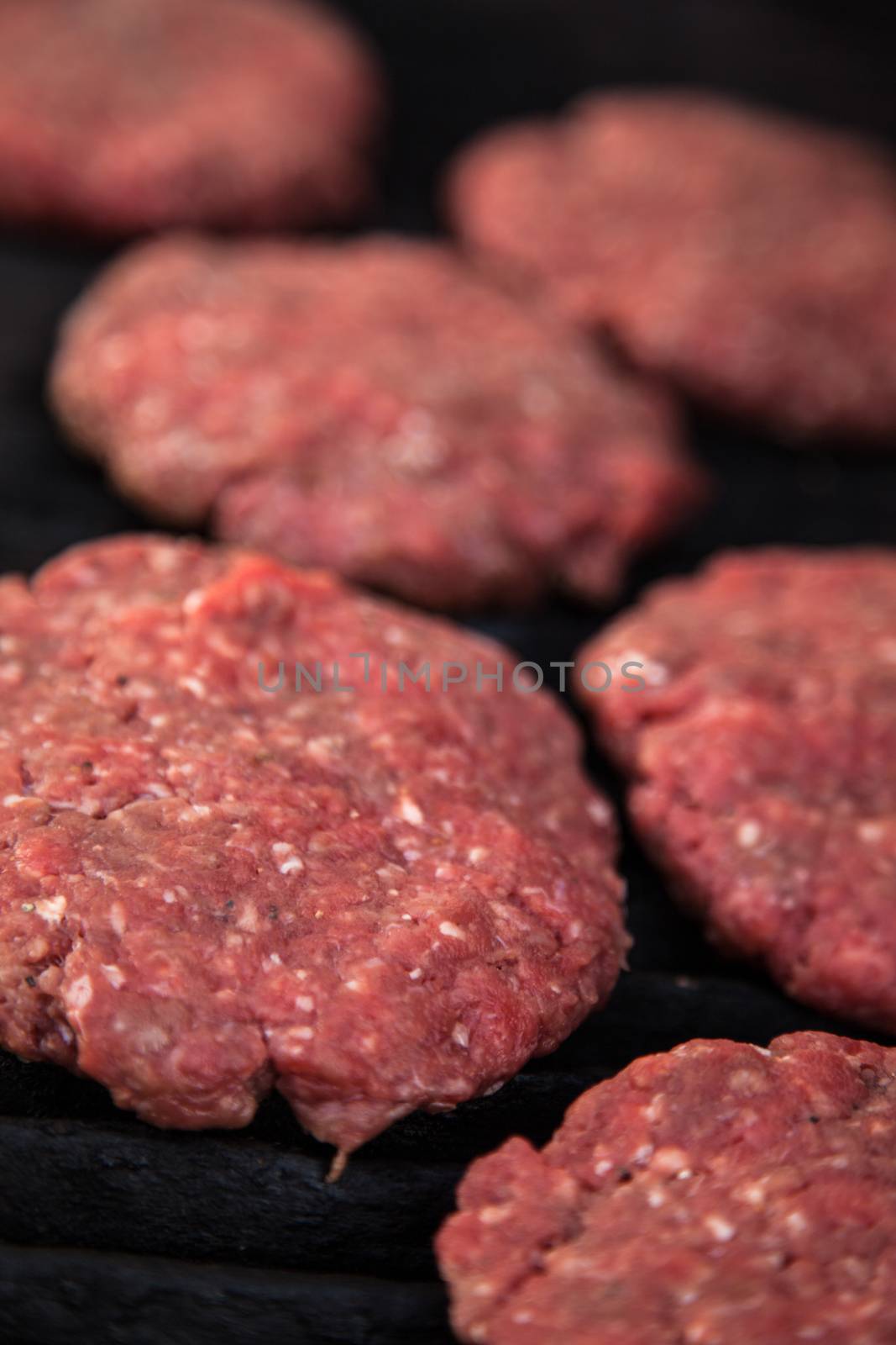 Raw hamburgers on the grill by Izaphoto