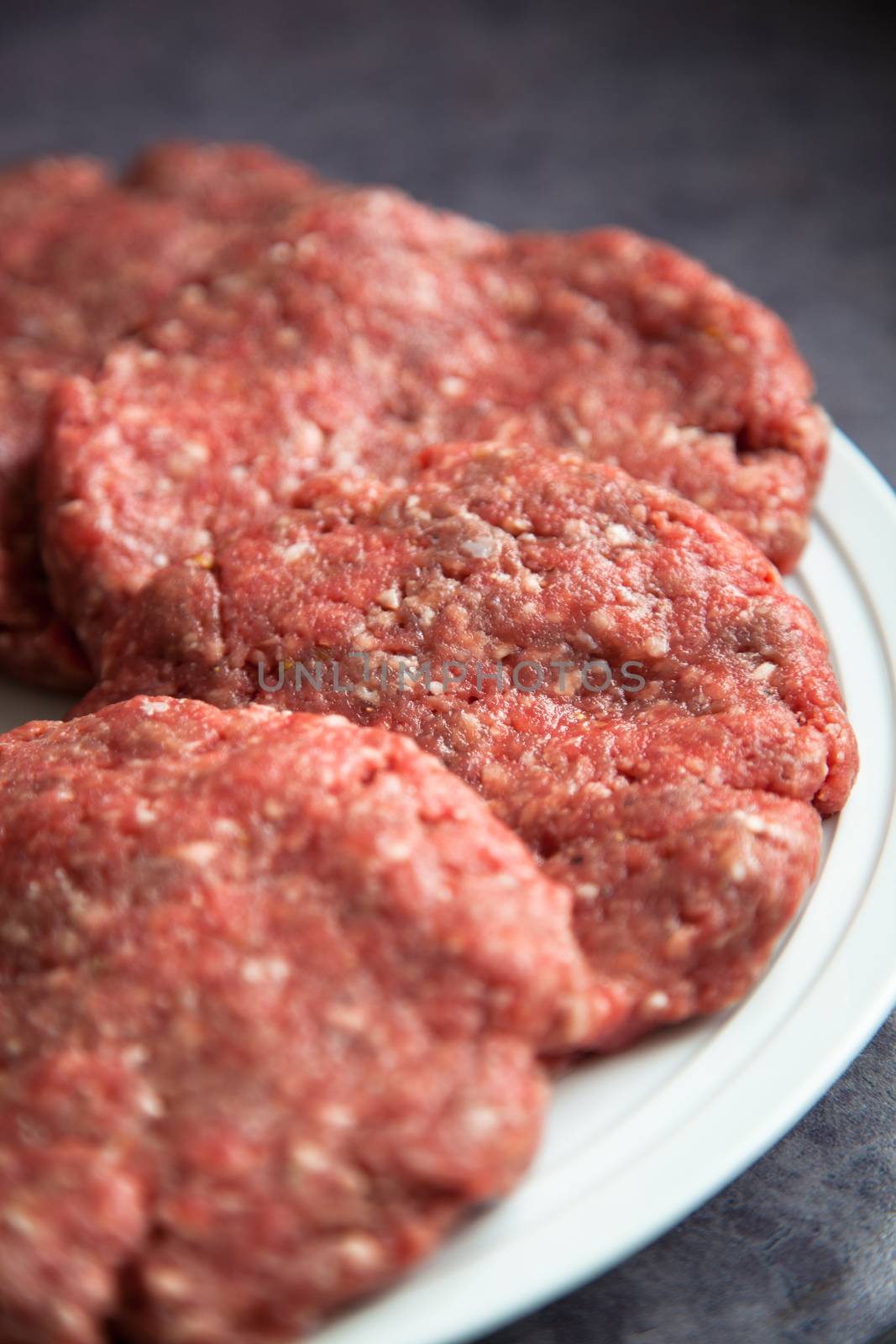 Raw fresh hamburgers on a white platter