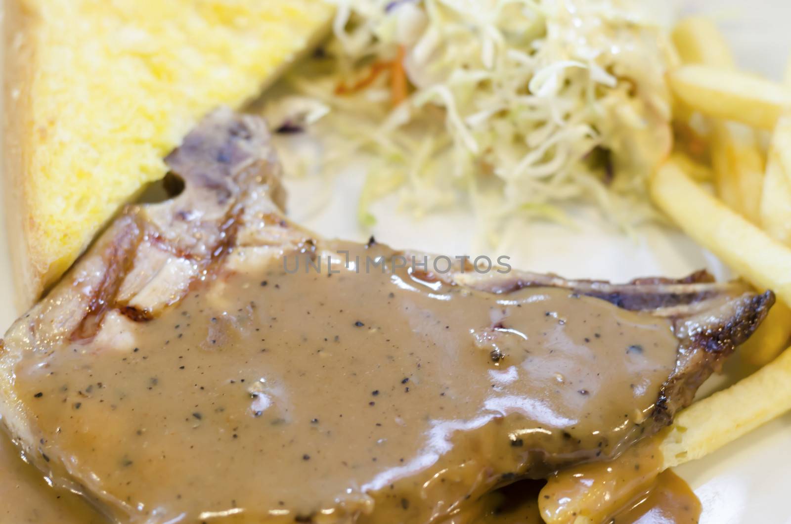 food steak on white dish with salad and bread