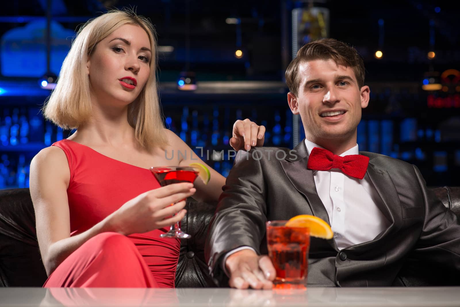 couple in a nightclub on the couch with a drink, have fun