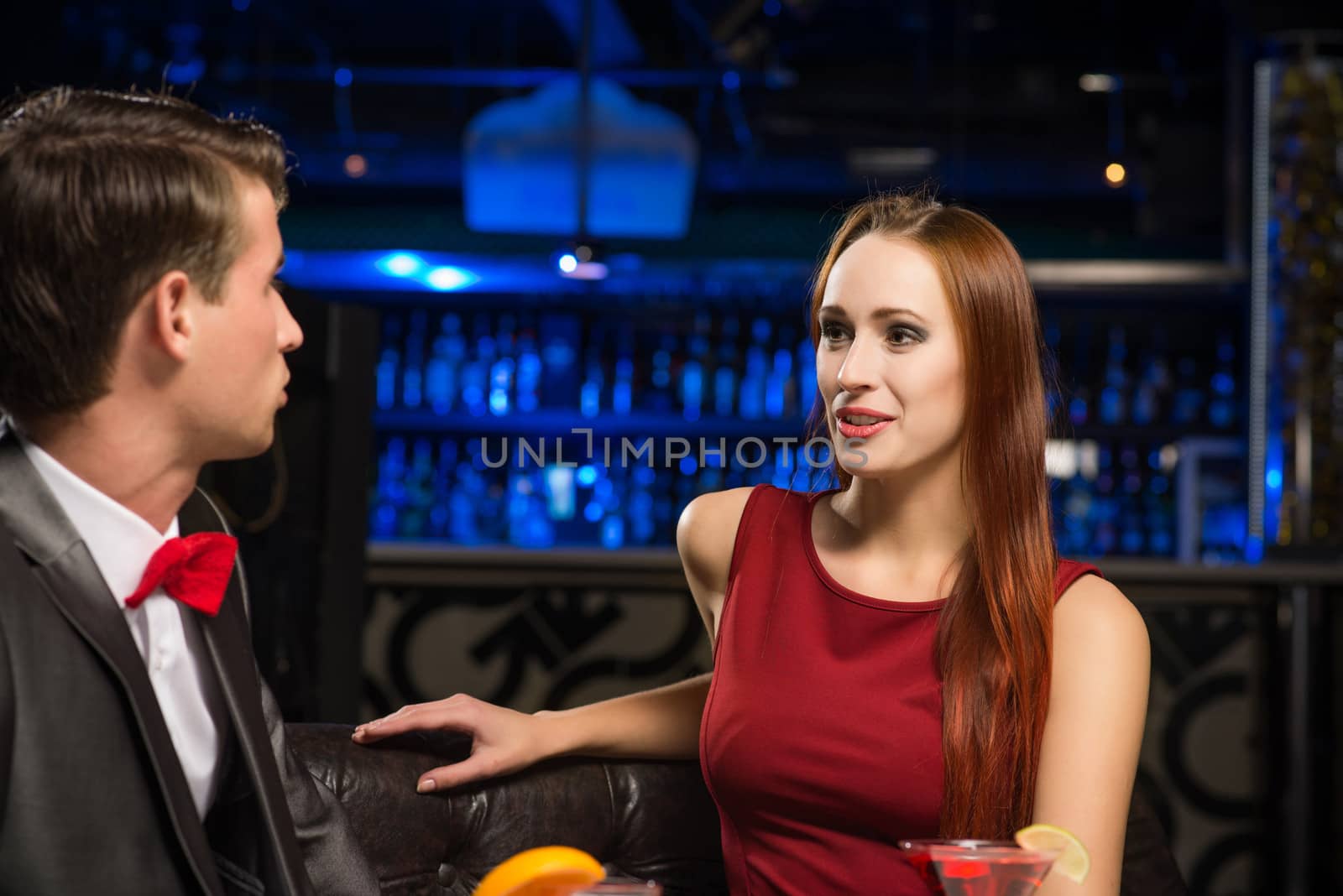 portrait of a woman in a nightclub, sitting on the couch and talking with man