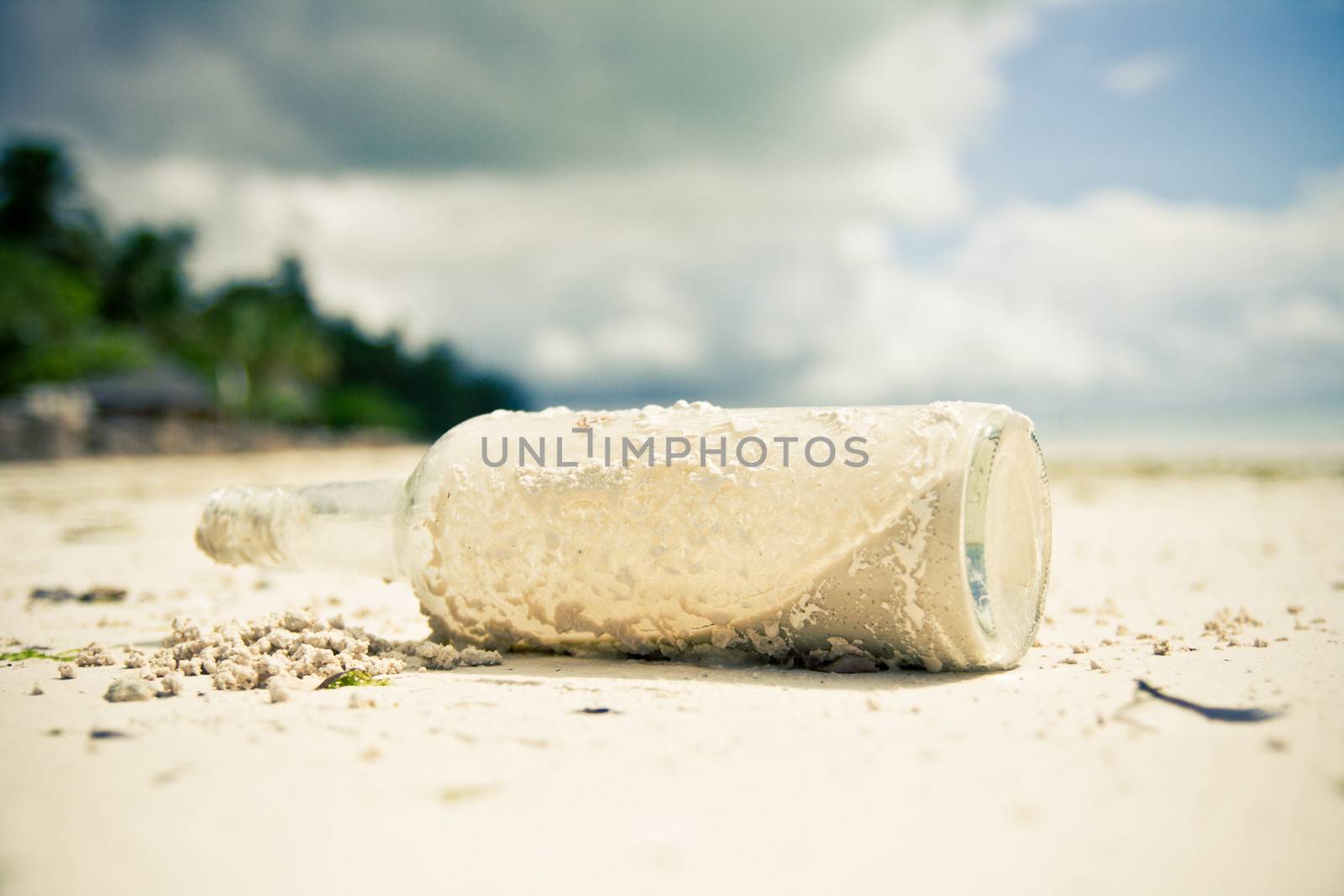 Glass bottle laying on a beach by photovibes