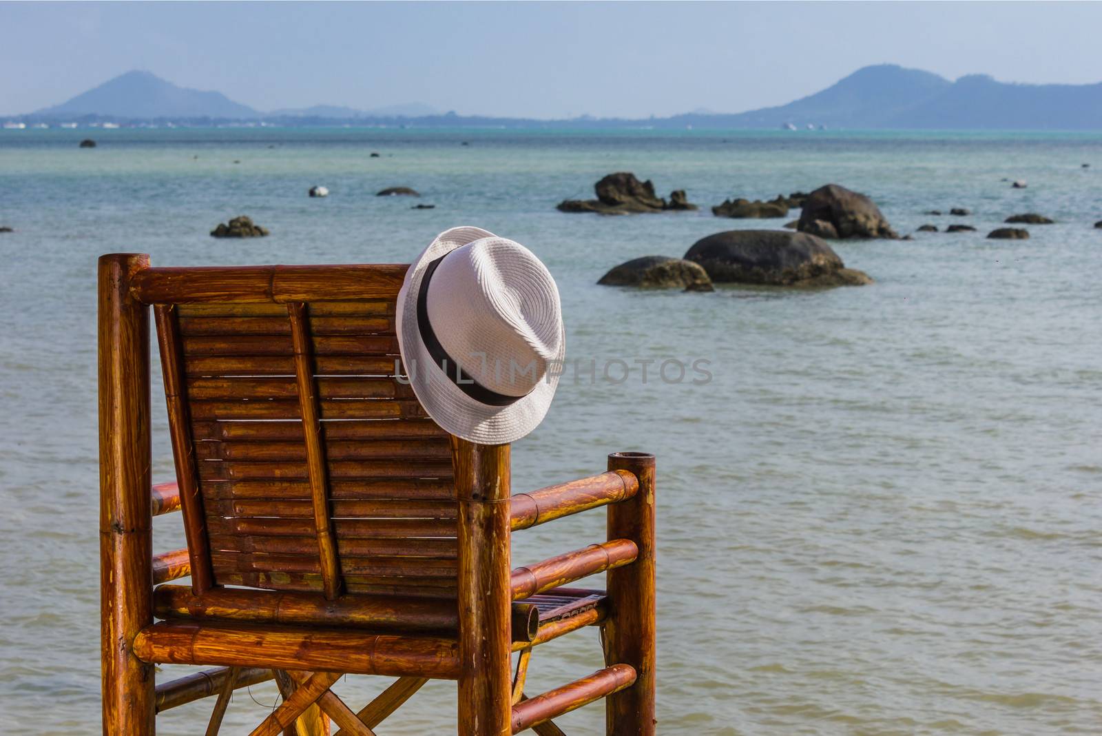 Hat hangs on a wicker chair on the background of the sea