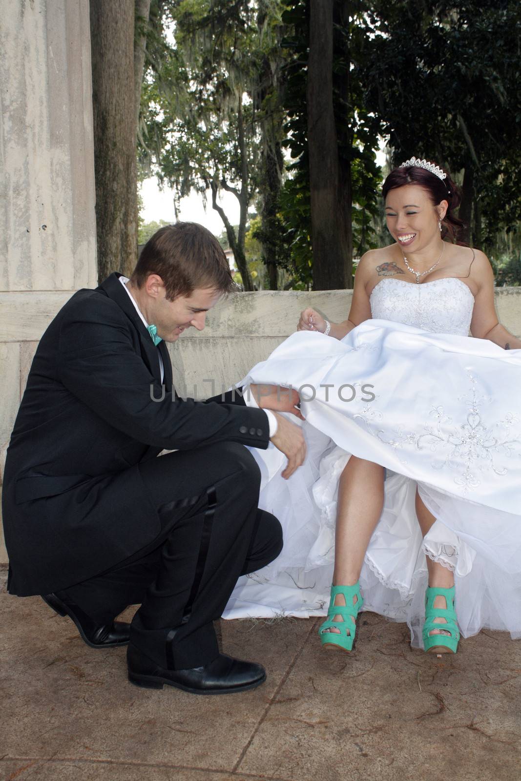 A handsome groom prepares to remove the garter from his bride's leg.
