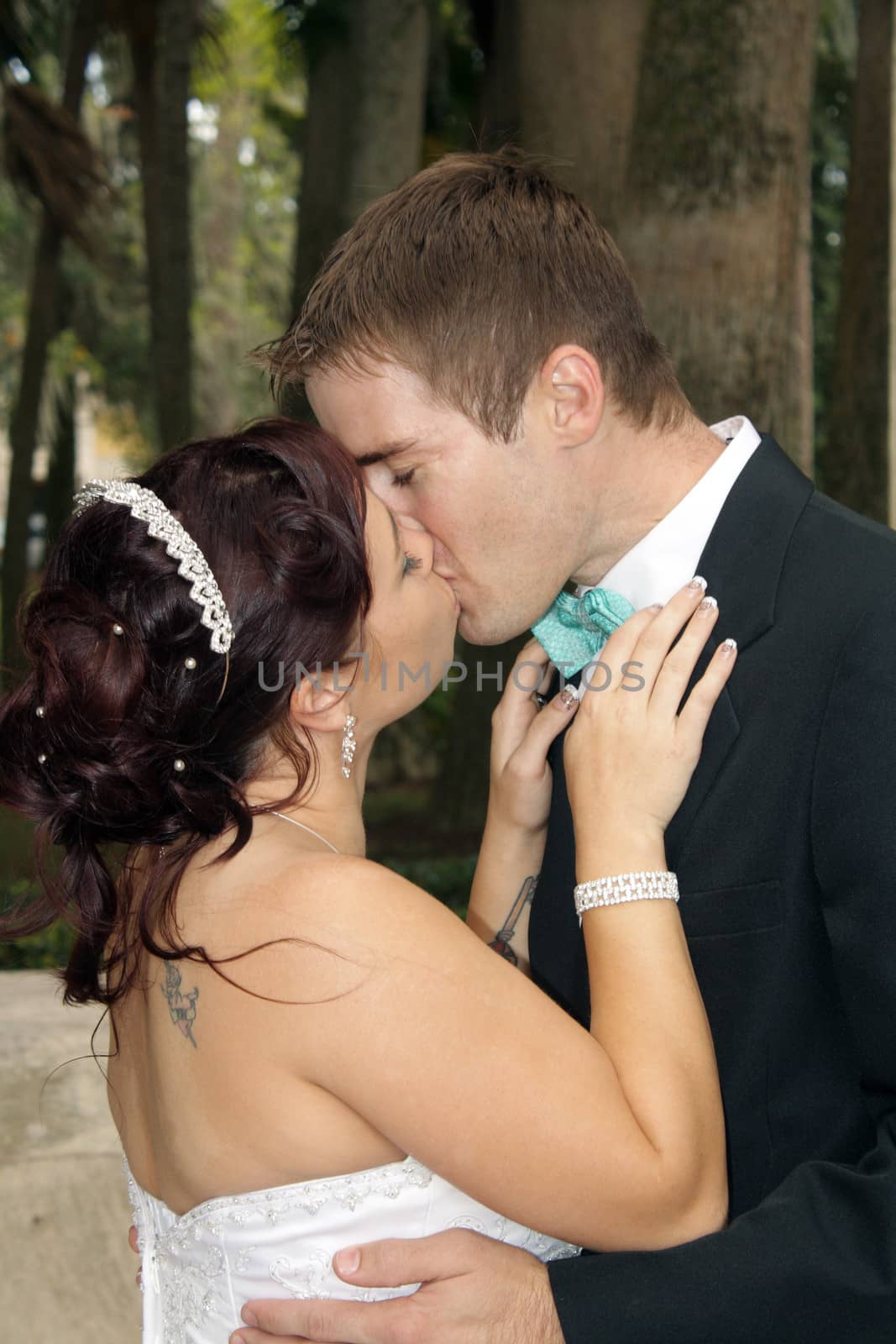 A handsome groom kisses his beautiful bride outdoors.