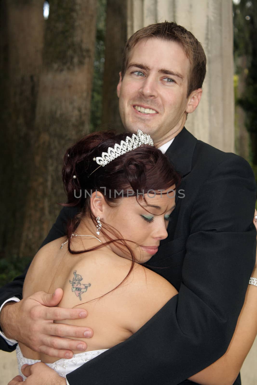 A handsome groom embraces his bride outdoors.