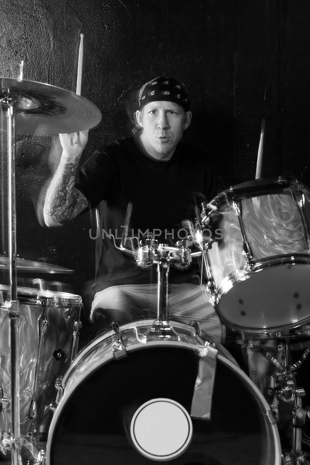 Photo of a drummer playing his kit. Visible movement on the head, arms and drumsticks.