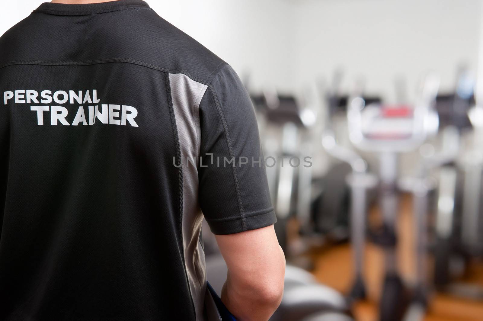 Personal Trainer, with his back facing the camera, looking at a gym