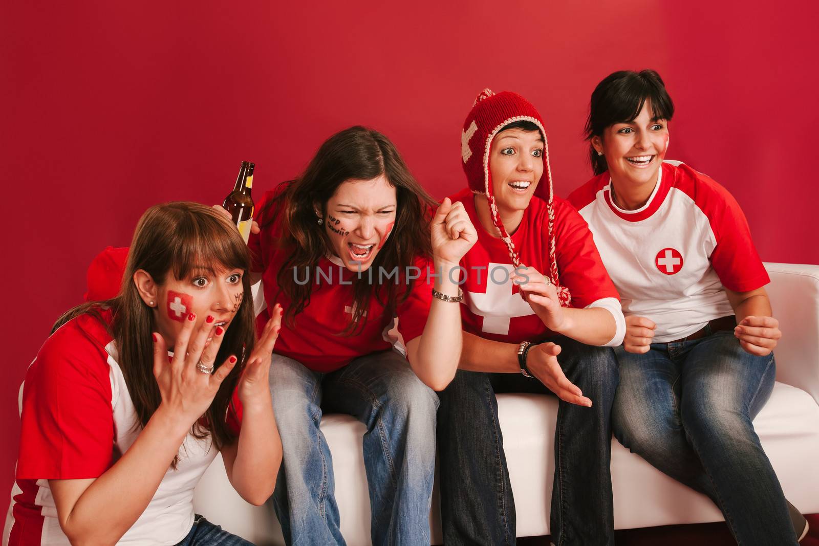 Photo of female Swiss sports fans watching television and cheering for their team.
