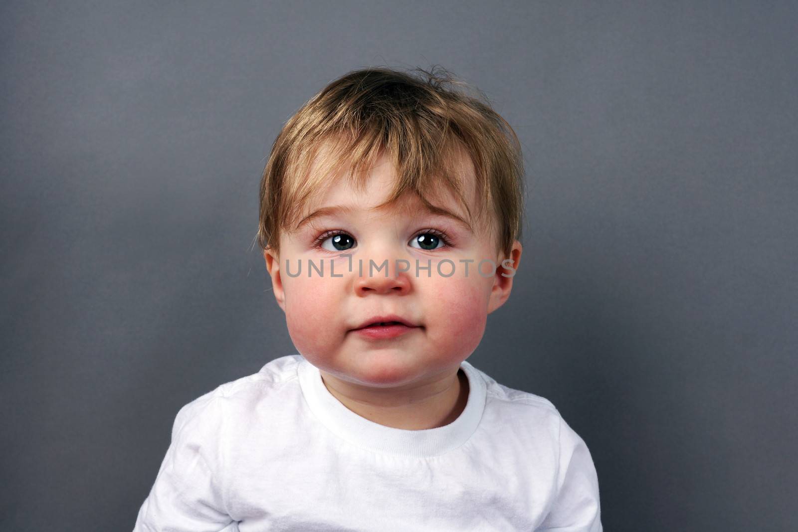 Portrait of cute little blond baby boy or toddler over grey background