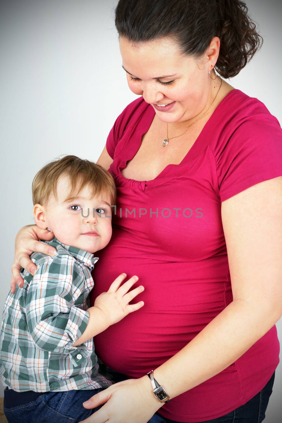 Beautiful pregnant woman hugging her cute little toddler boy