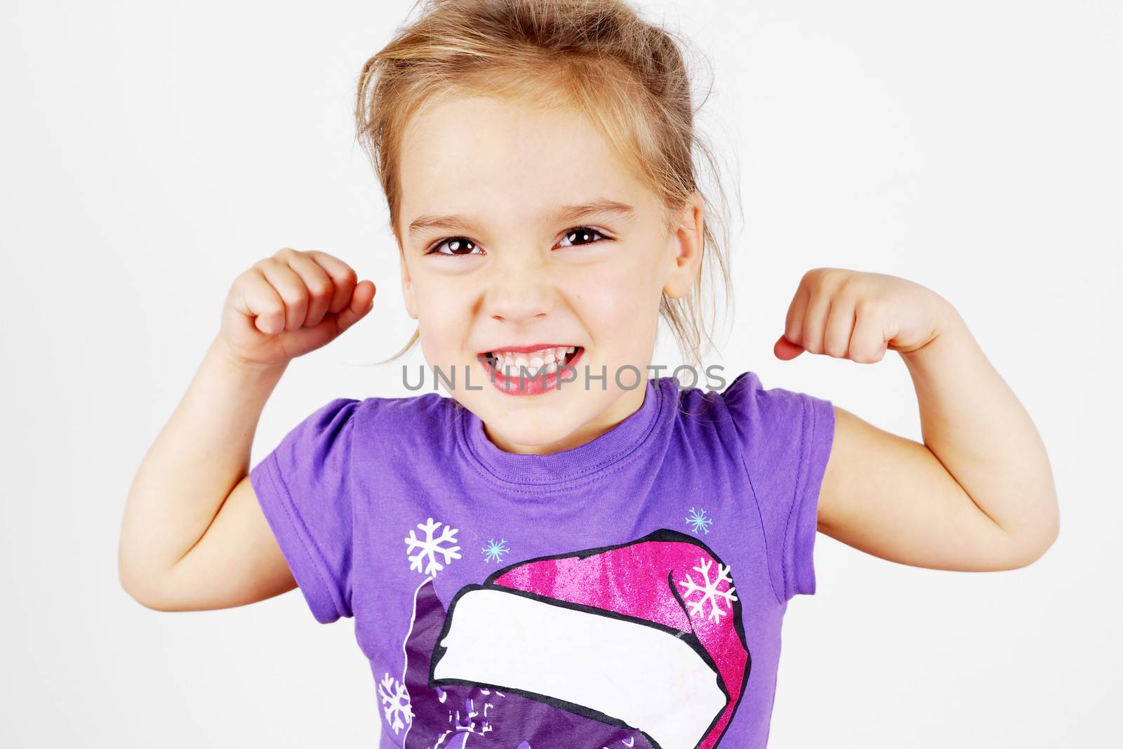 Cute and funny little blond girl showing her muscle