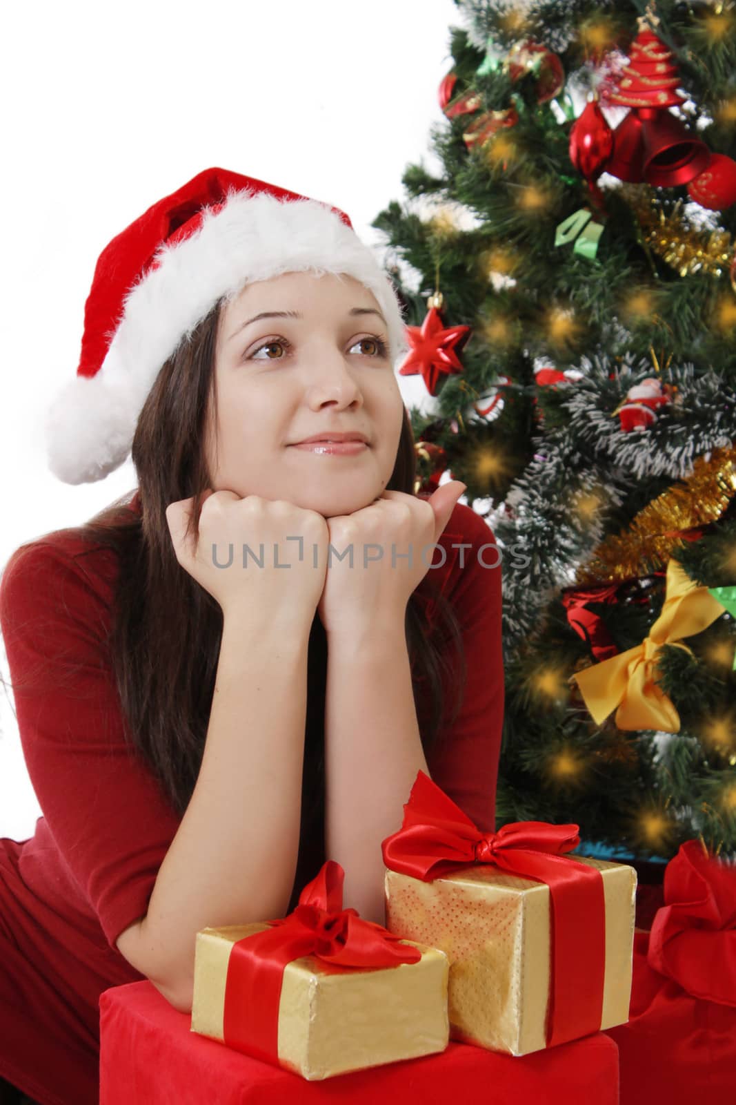 Dreaming Santa girl with gifts sitting under Christmas tree