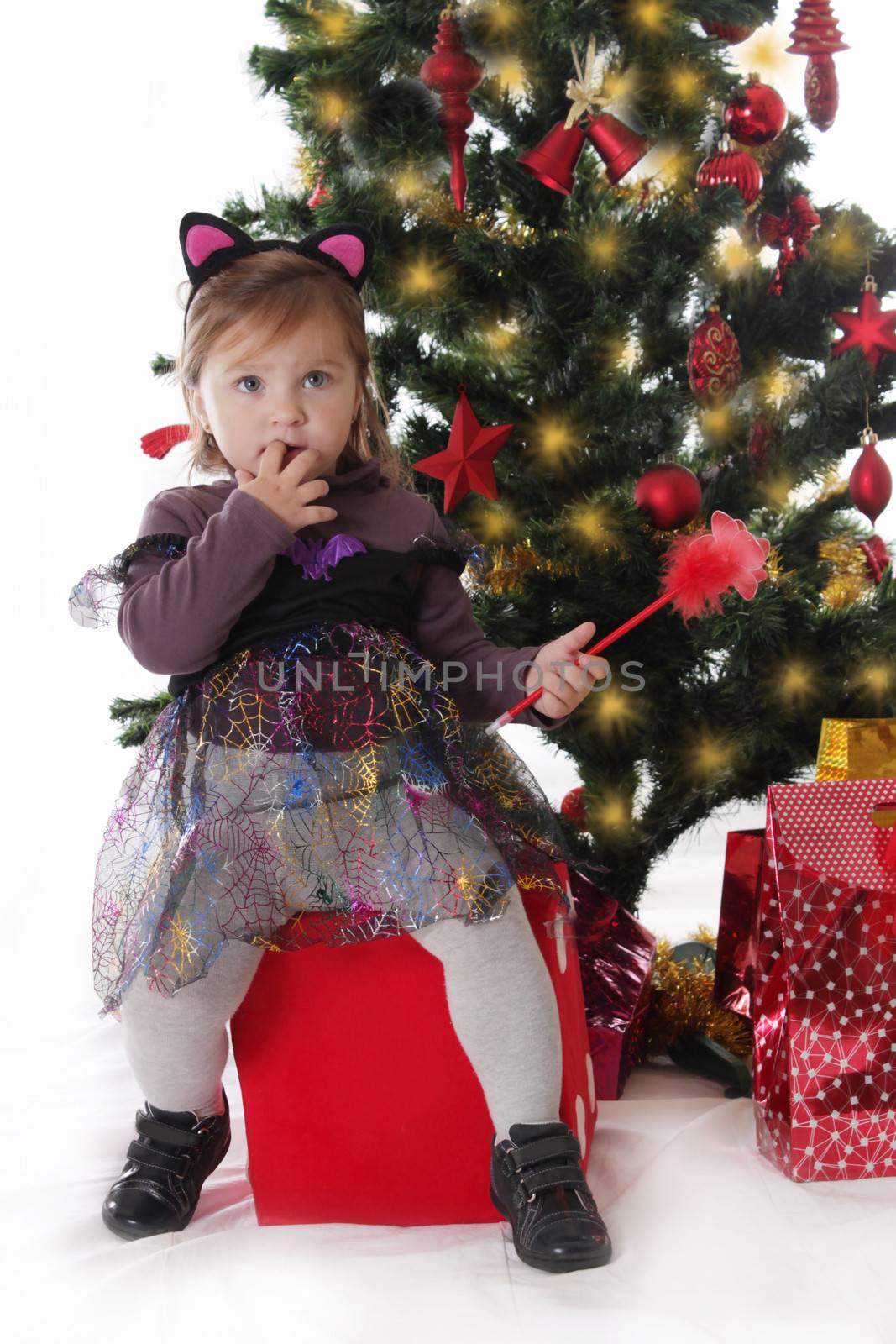 Little girl in fairy costume sitting under Christmas tree