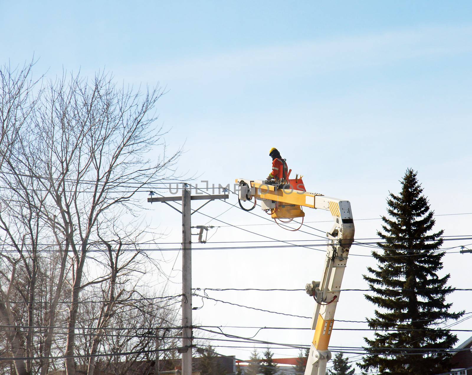Worker from electrical company making repairs duing winter, ice rain.