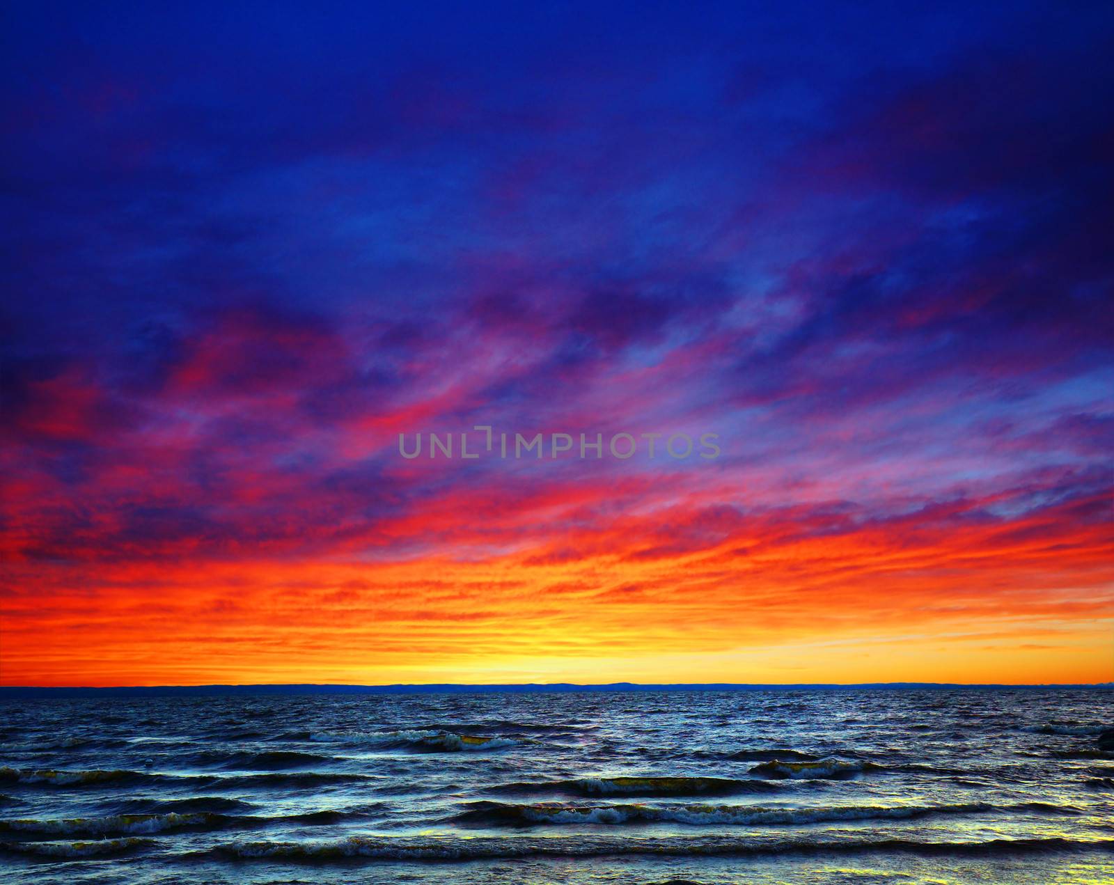 Beautiful colorful sunset over wavy waters, sea or ocean