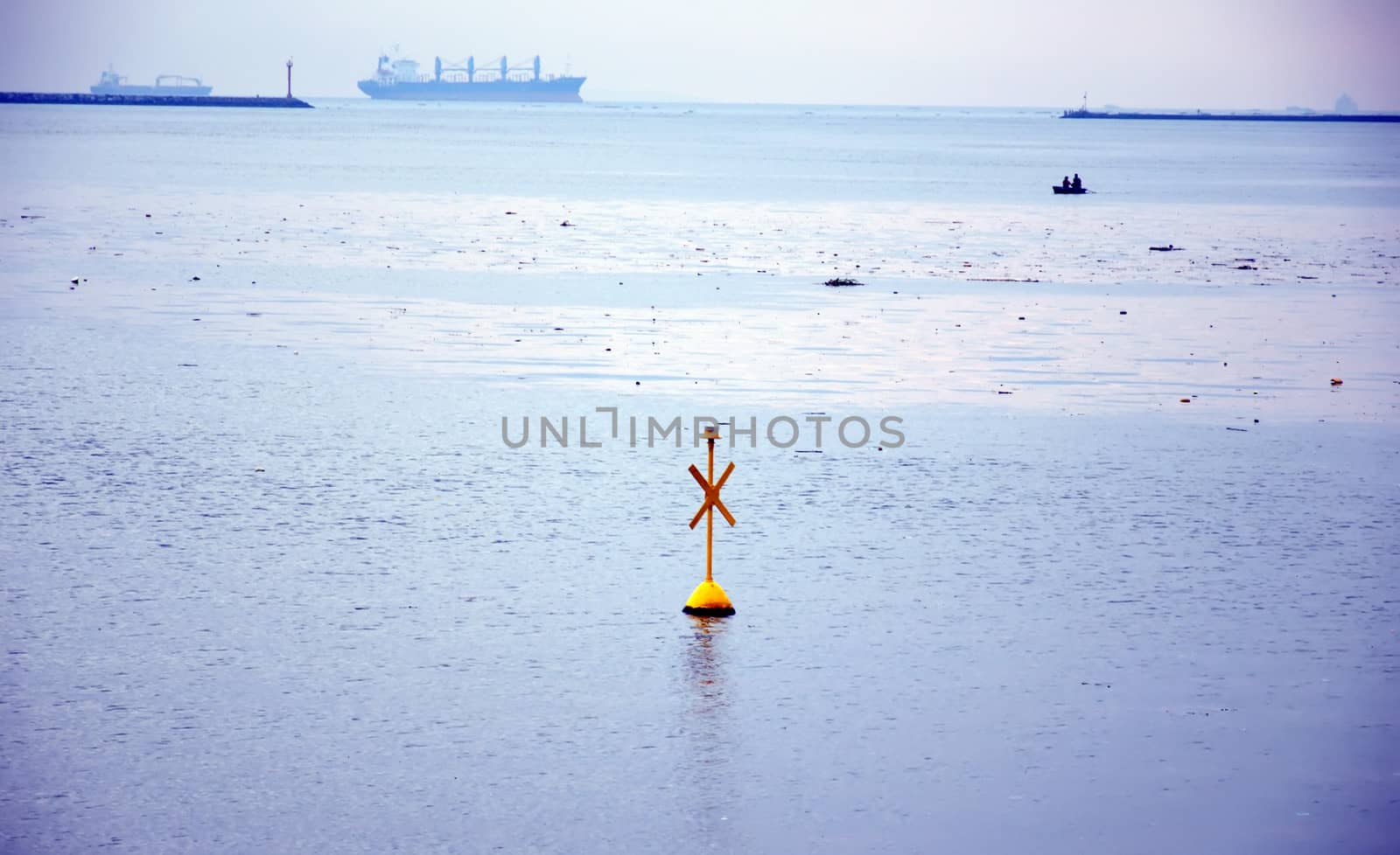 yellow buoy marker sign and boat in the ocean