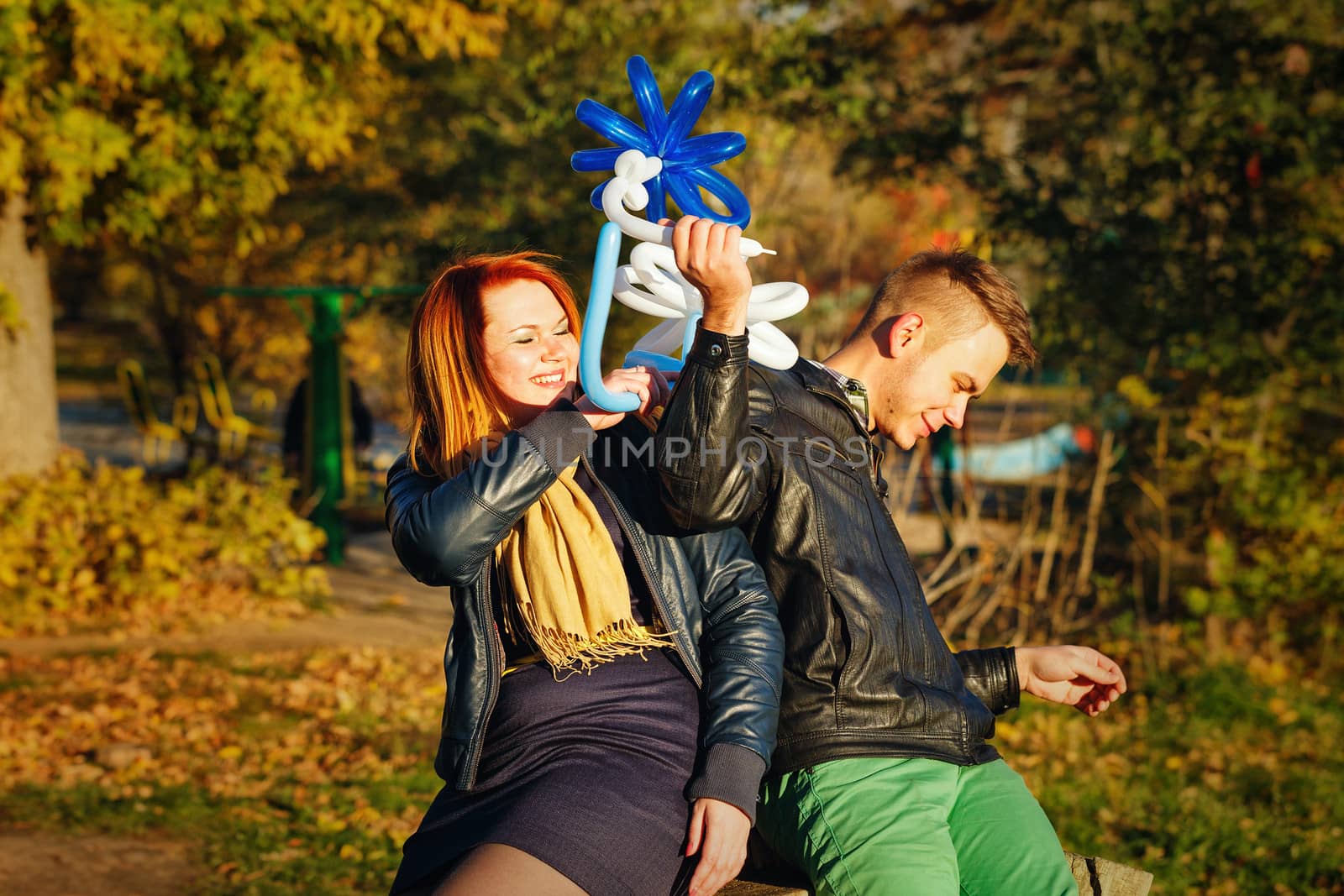 Couple playing with balloons in autumn park on a sunny day