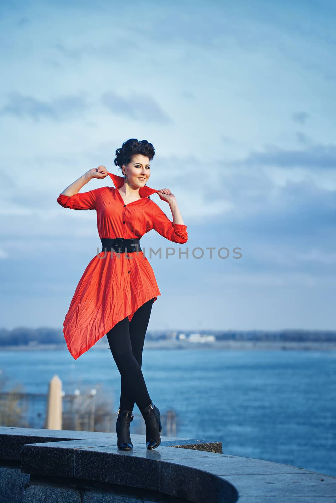 Attractive girl in red shirt walking along waterfront
