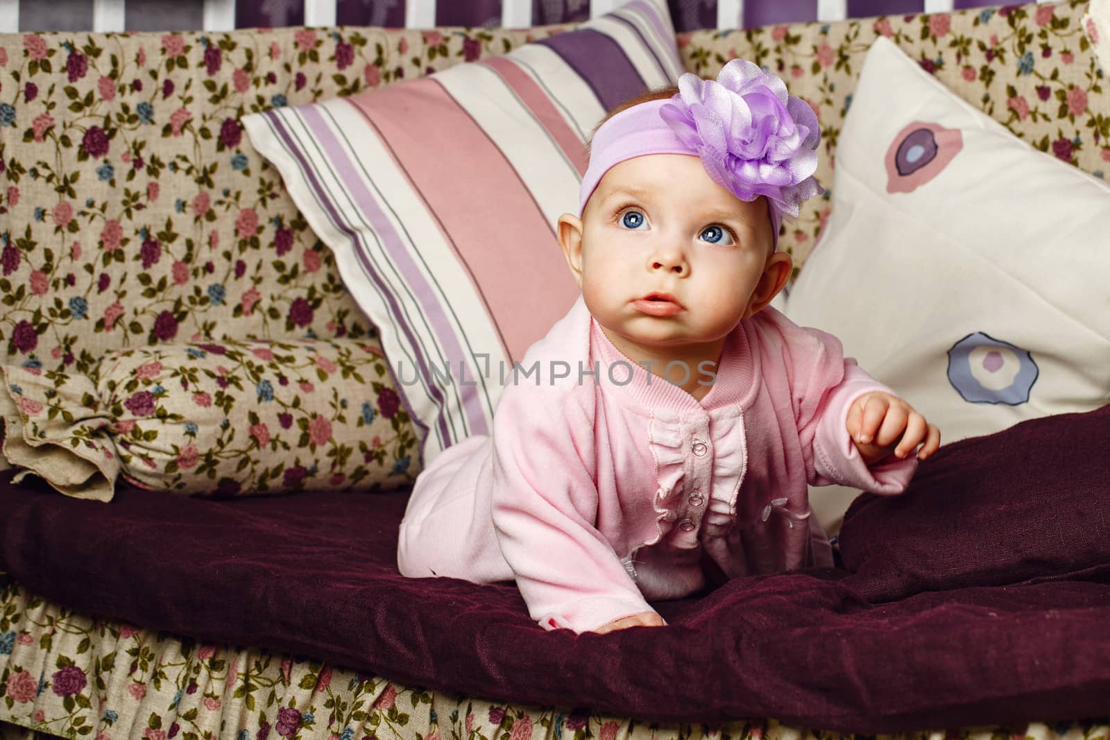 Little girl with bow on her head sitting on couch