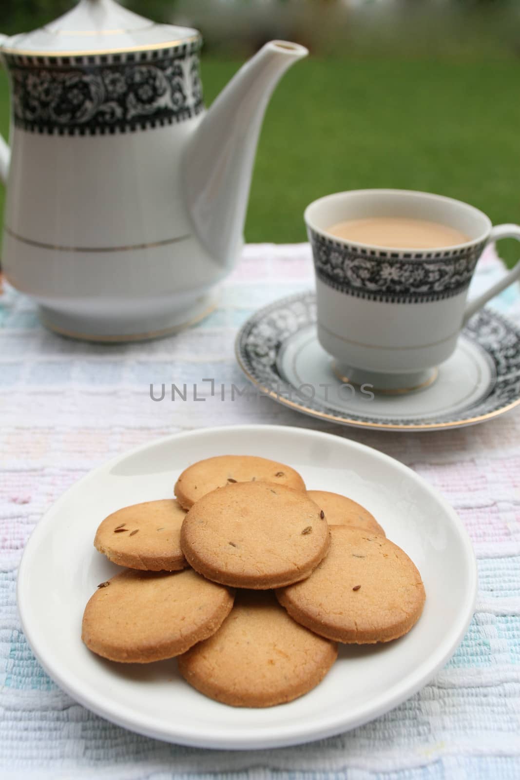 Plate full of biscuits served with tea pot and a cup