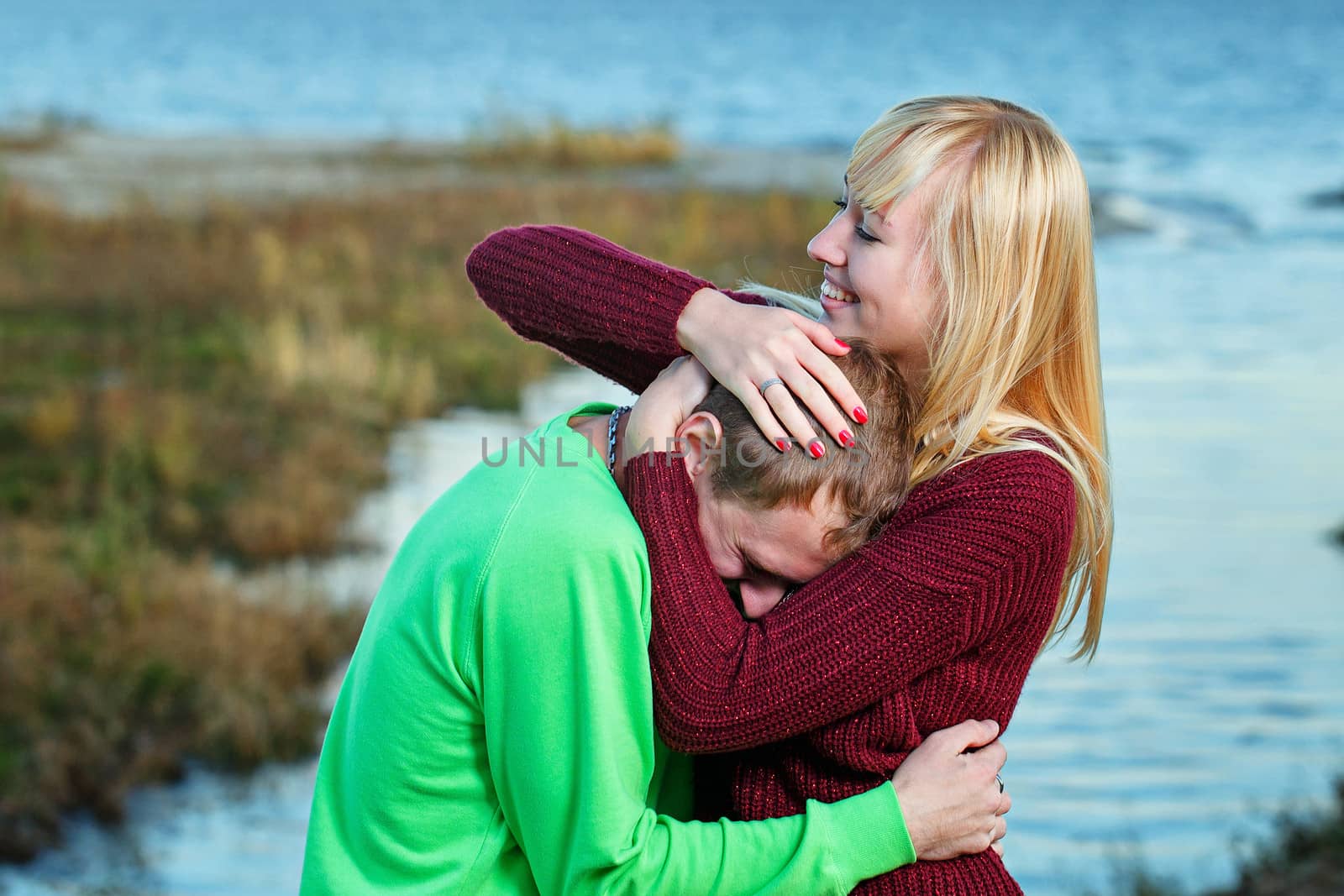 Young couple tenderly and lovingly embrace each other on banks of river