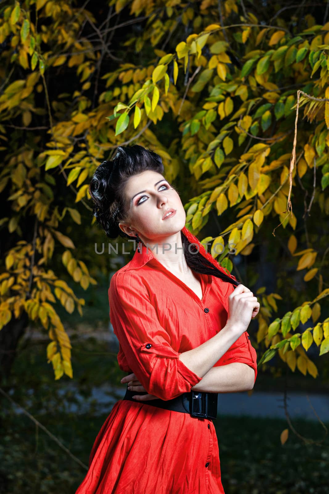 Young attractive girl in red shirt and with makeup close-up portrait in autumn park