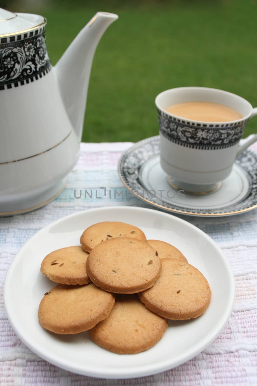 Plate full of biscuits served with tea pot and a cup