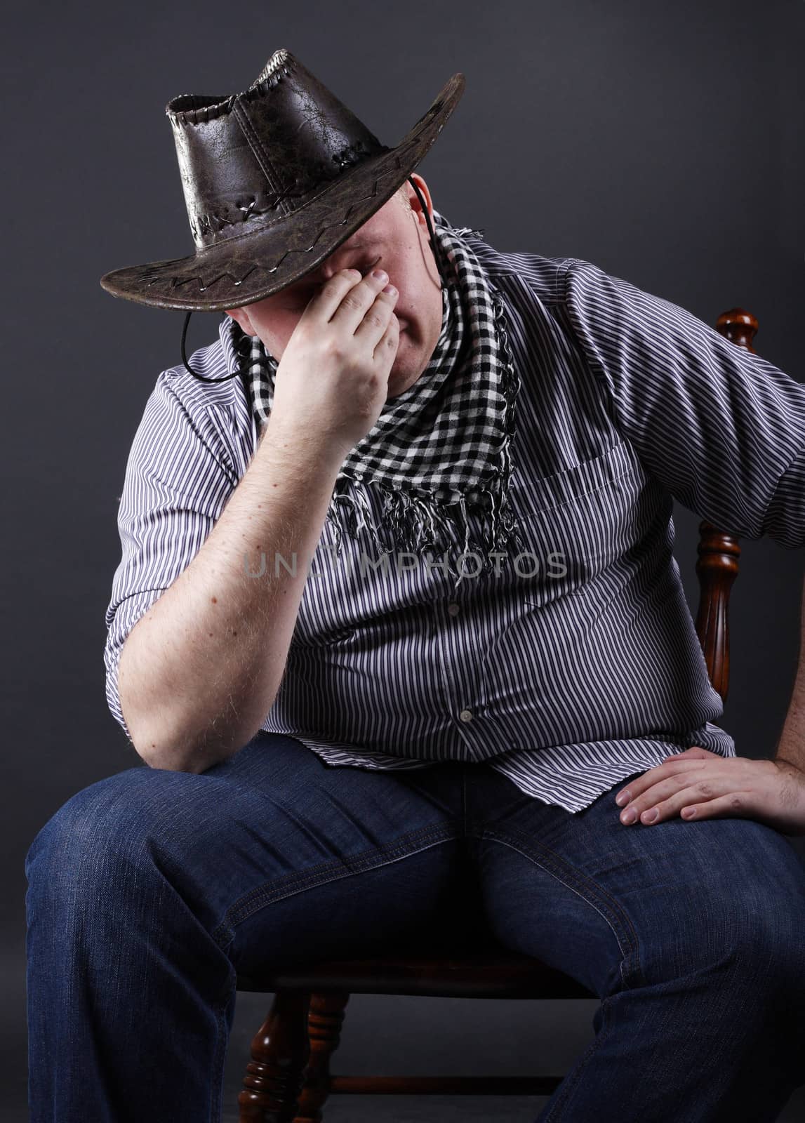 Tired man sitting on a chair at a dark background