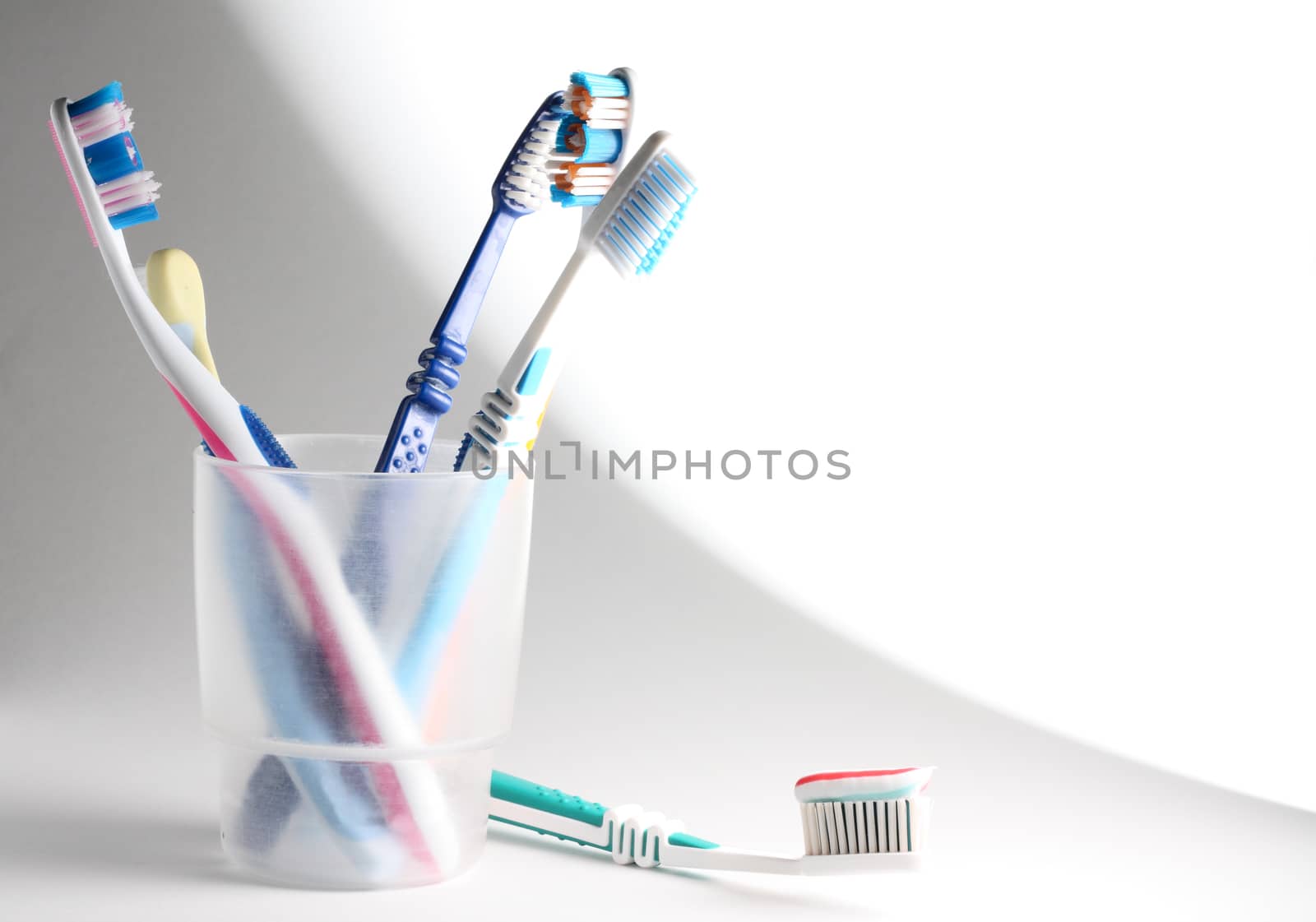 Some toothbrushes in a plastic glass