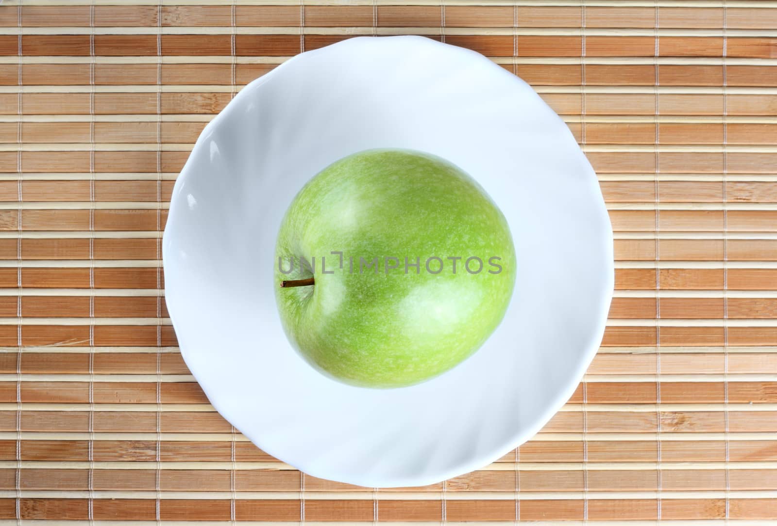 Green apple on the saucer at the wooden texture background