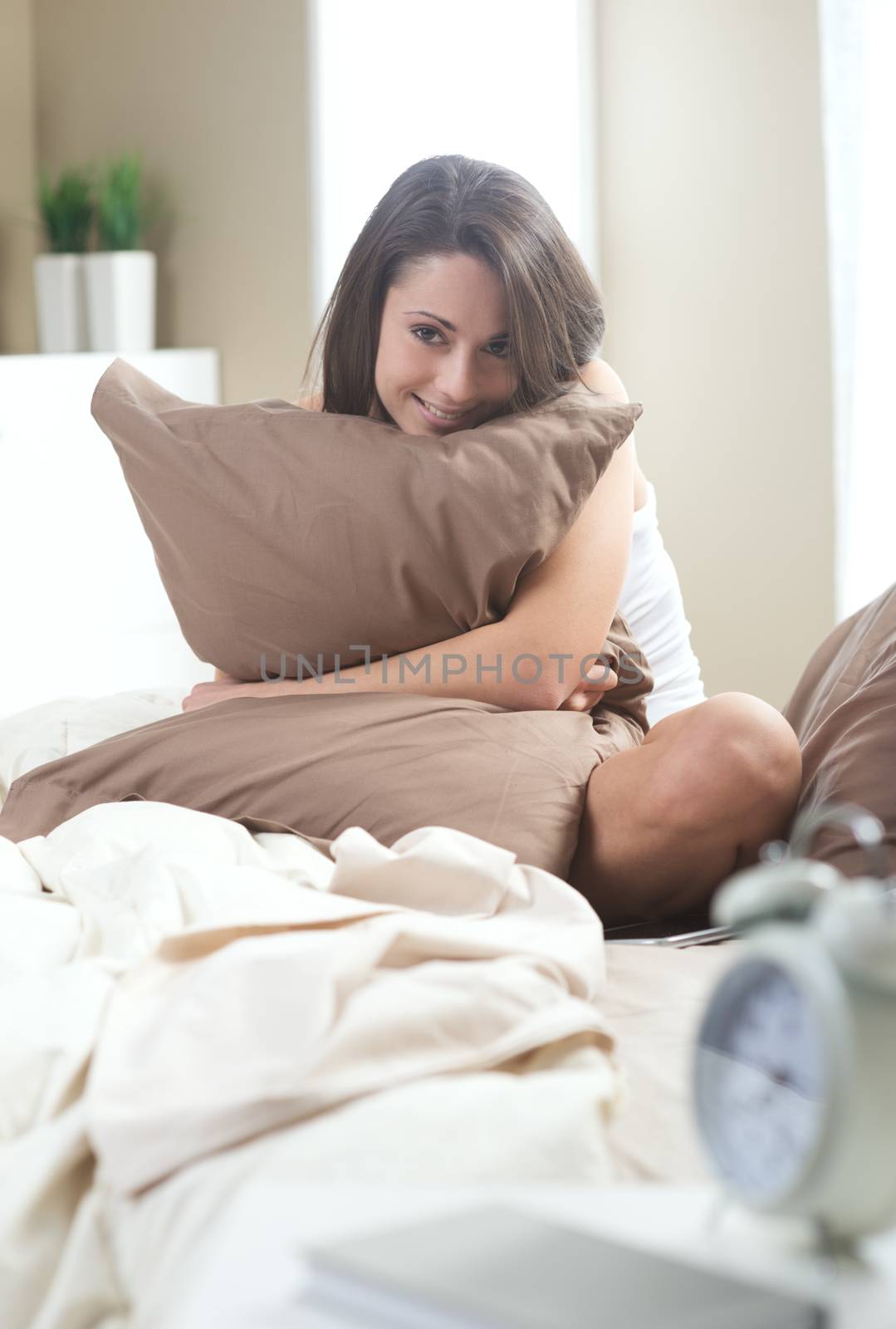 Young woman embracing her pillow in the morning