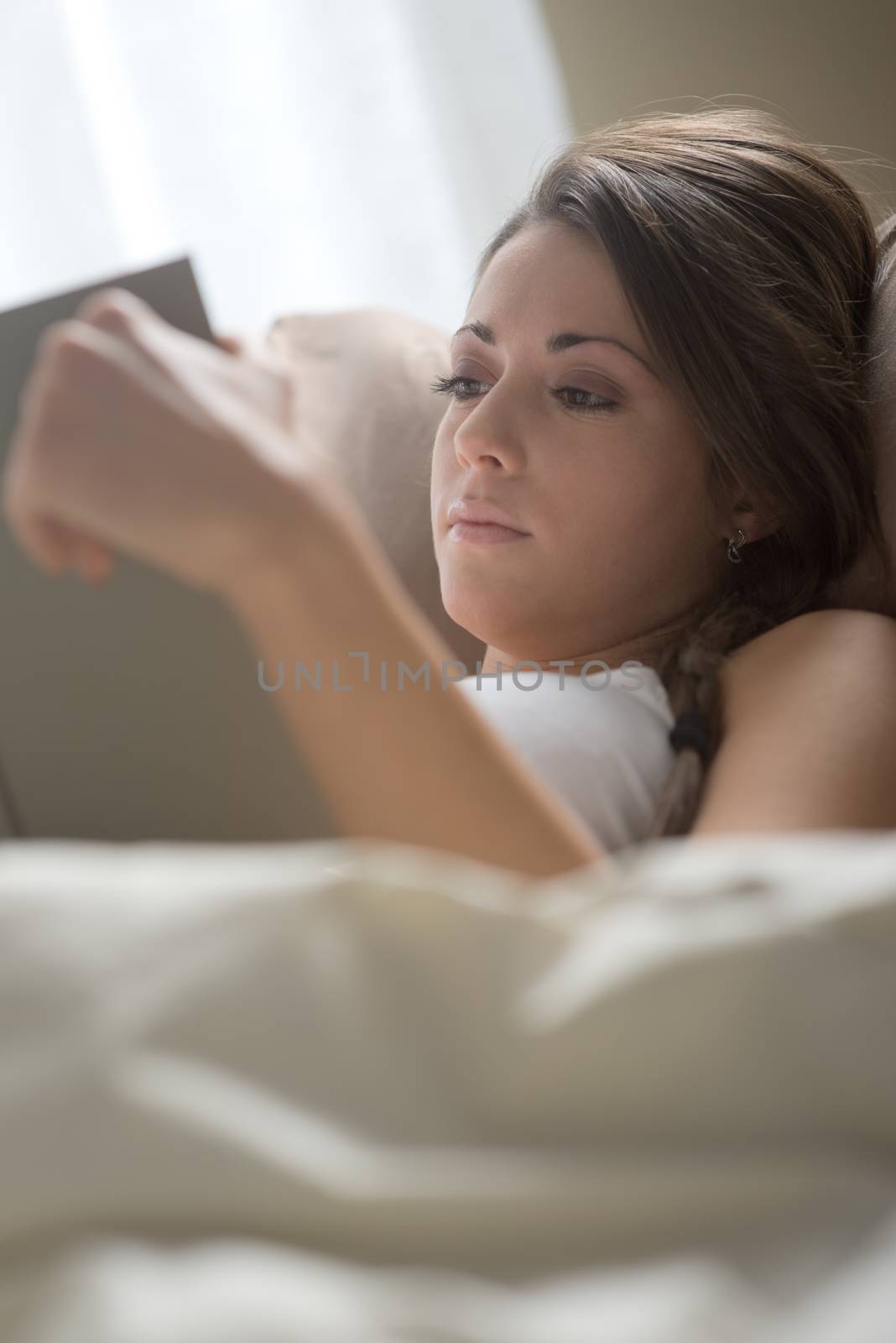 Woman lying in bed while reading a book 