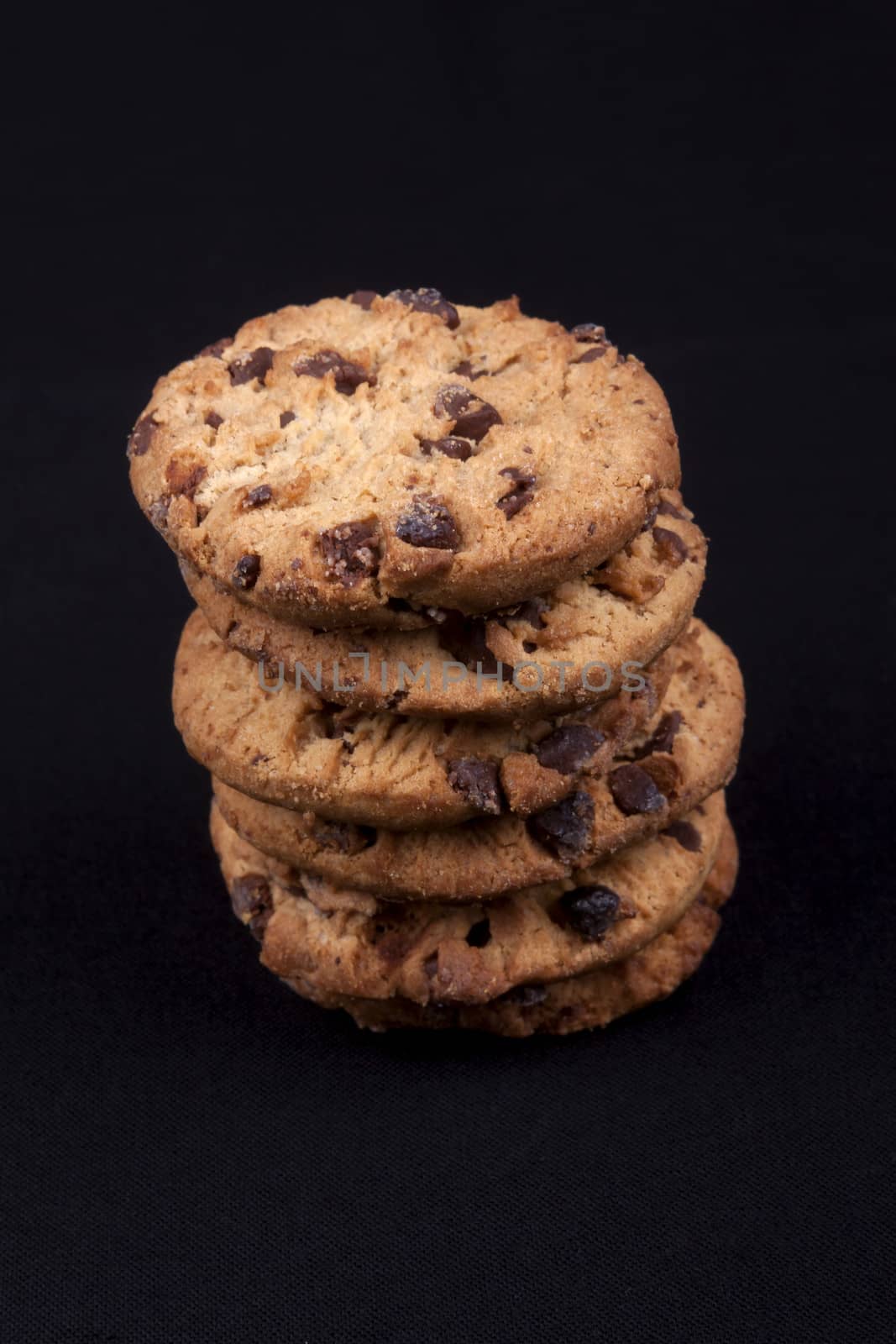 A piles of chocolate chips cookies isolated on black background.