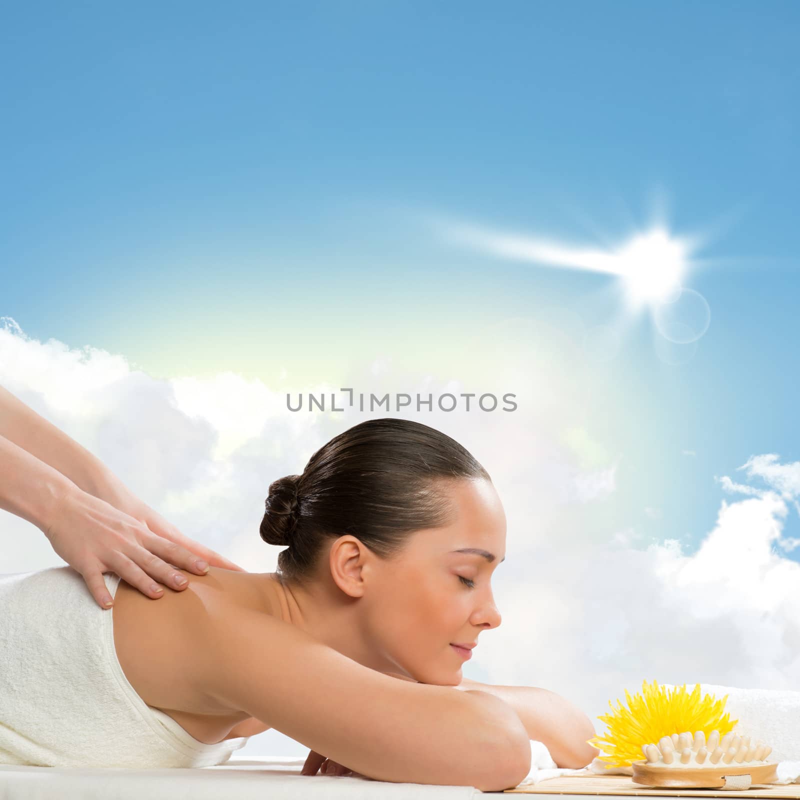 beautiful spa woman lying on the couch, in front of her flower and rolled towel