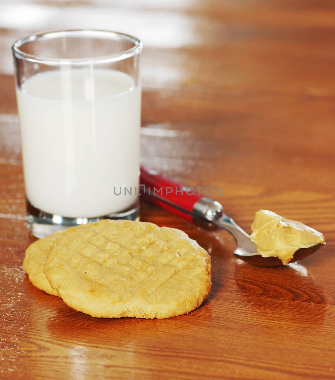 Homemade peanut butter cookies with milk and spoon over wooden table.