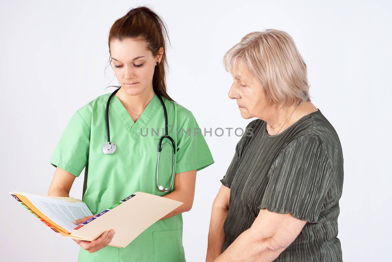 Young woman nurse or doctor and senior reading medical file