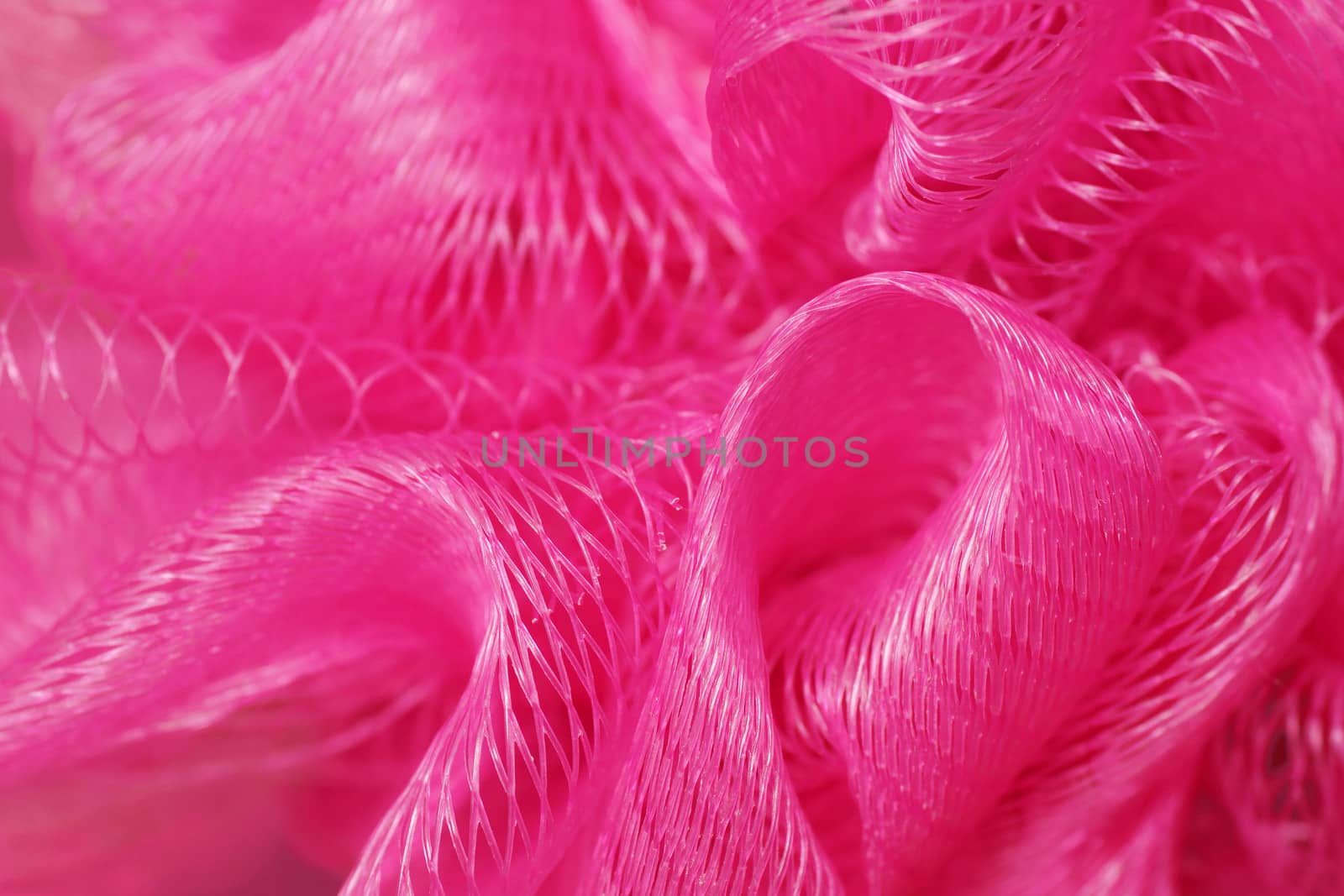 Macro of a pink bath puff or sponge, plastic mesh detail, texture background.