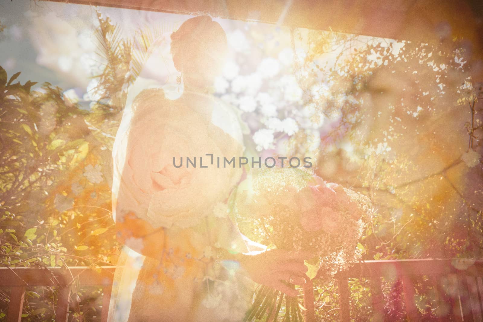 Bride holding her bouquet standing on an outdoor verandah backlit by sun flare