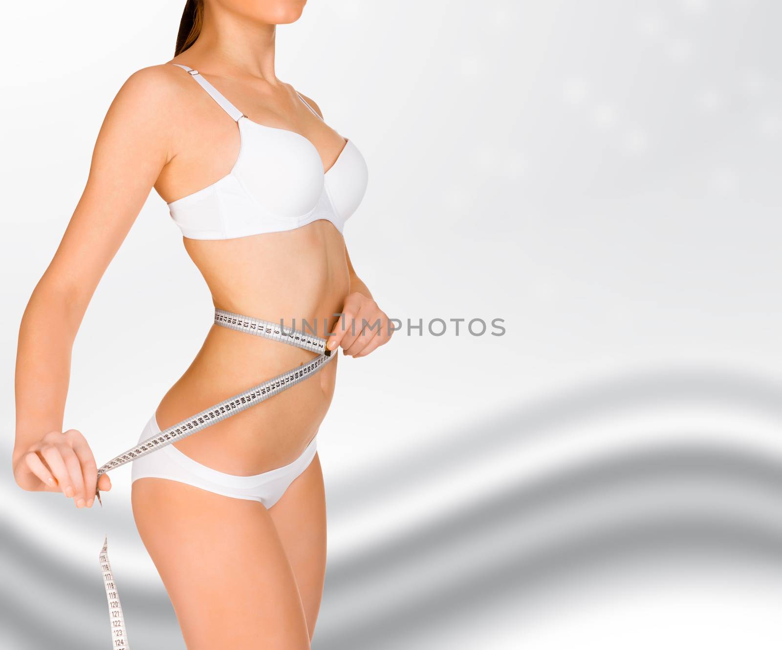 fit young woman measuring her waistline by Nobilior