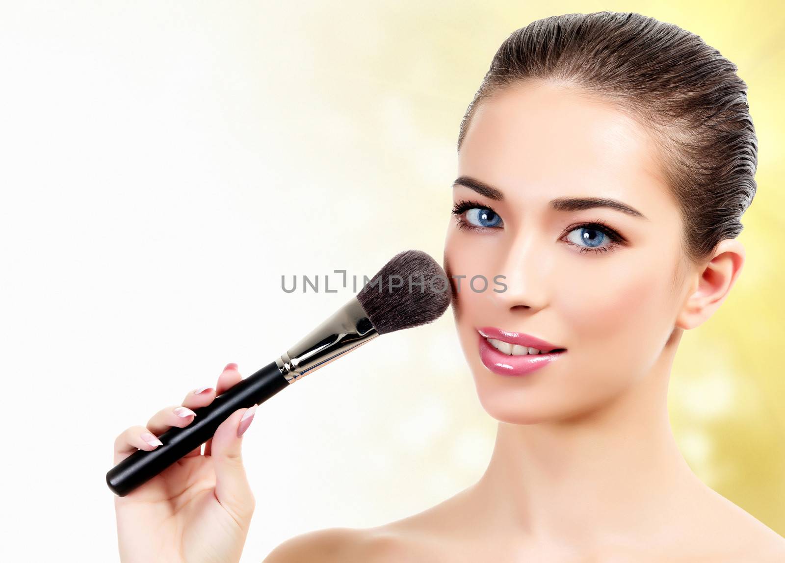 woman with cosmetic brushes against an abstract blurred backgrou by Nobilior